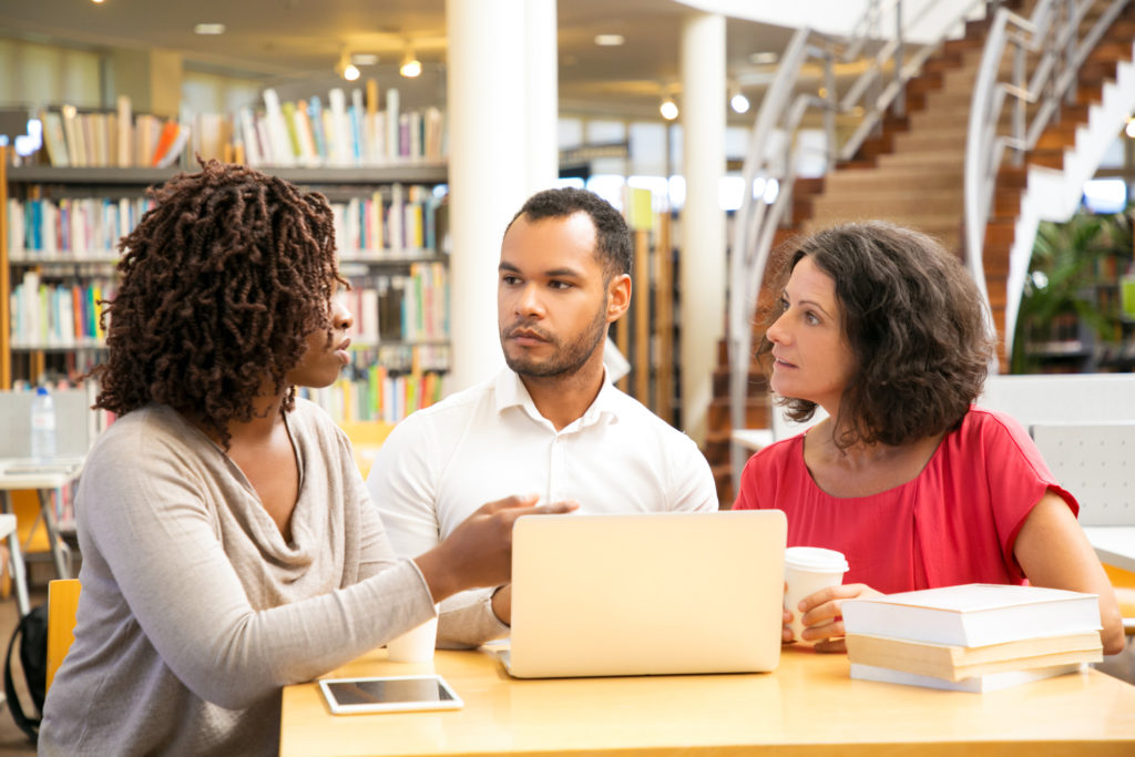 Three people in front of a laptop