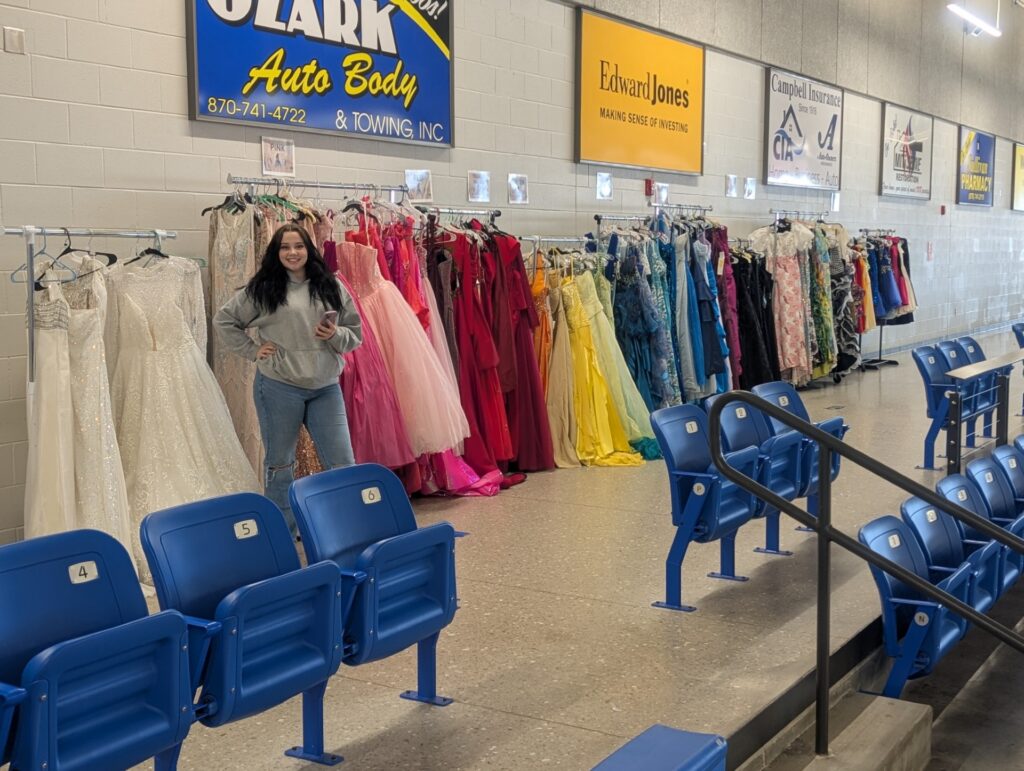 A Key Club student at Harrison High School in Harrison, AR, with donated dresses for “The Promise Project.”